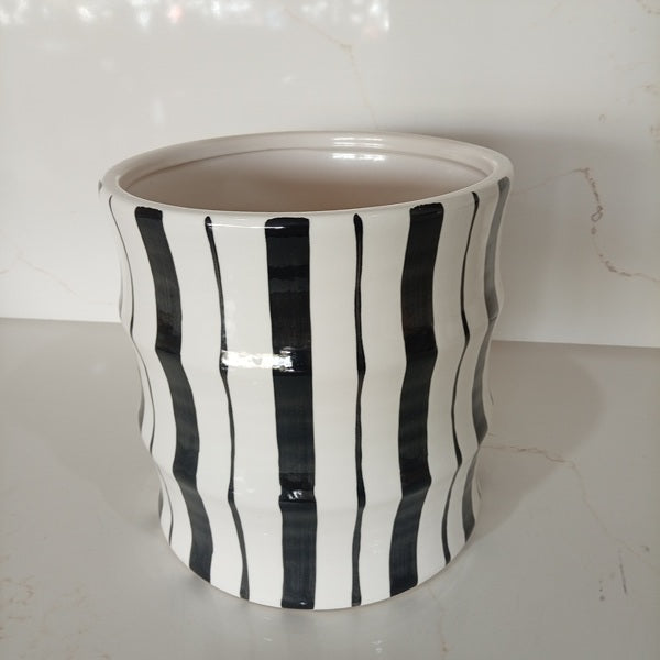 Contemporary fluted ceramic vase featuring hand-painted black vertical stripes on a glossy white glazed body.