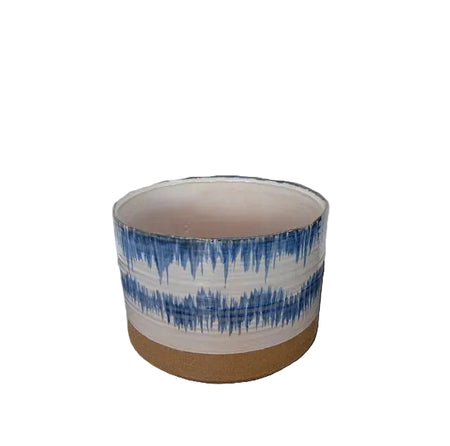 A cylindrical blue and white patterned ceramic planter with an unglazed terracotta base.