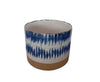 A cylindrical blue and white patterned ceramic planter with an unglazed terracotta base.
