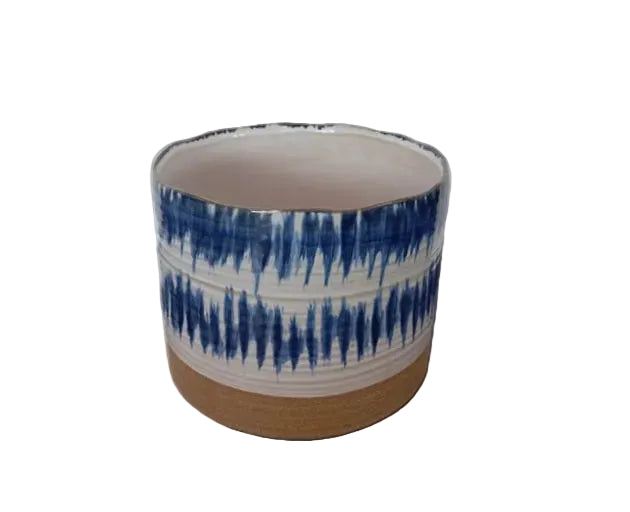 A cylindrical blue and white patterned ceramic planter with an unglazed terracotta base.

