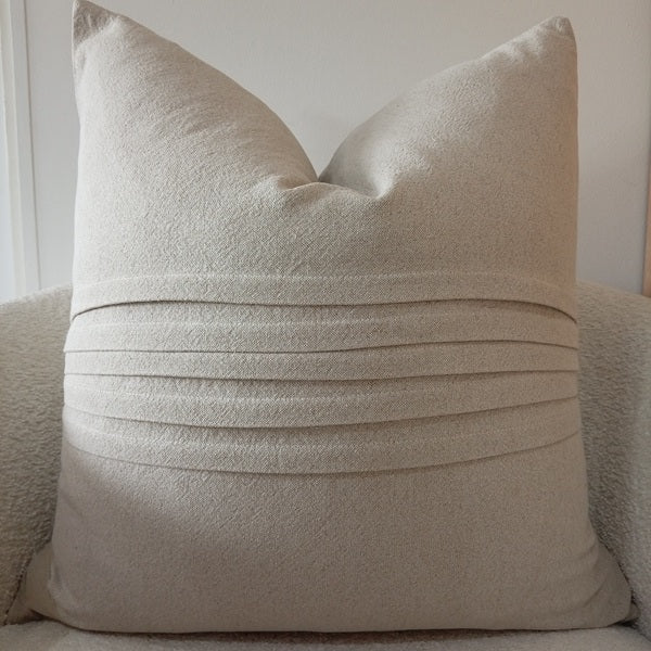Oatmeal-colored natural linen scatter cushion designed with horizontal stitched pleats and pin-tuck details across the centre.