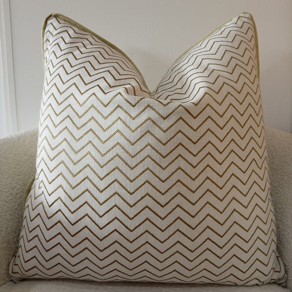 Textured off-white scatter cushion featuring a close-up of embroidered olive green and khaki zig-zag chevron patterns.