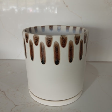 A cylindrical white ceramic planter pot featuring a decorative brown drip glaze pattern along the upper rim, sitting on a matching white saucer.