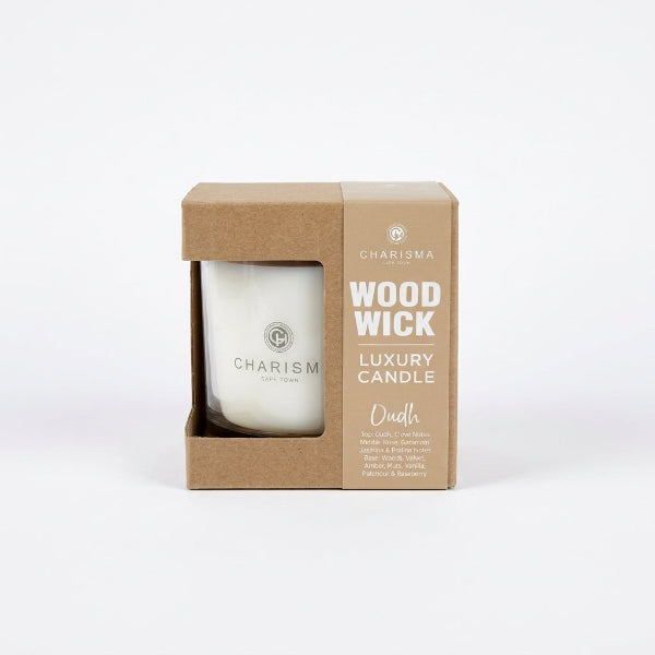 Charisma Wood Wick Luxury Candle in Oudh fragrance, highlighting its classic kraft gift sleeve showing the scent notes next to a clean white glass tumbler.
