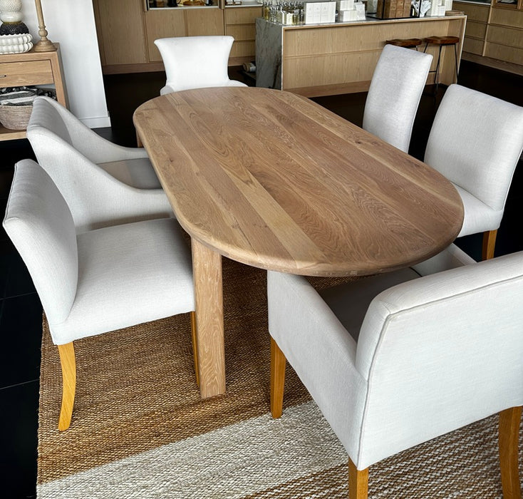 Top down view of a 2200mm solid oak oval dining table shown alongside dining chairs for scale. Table sold individually.