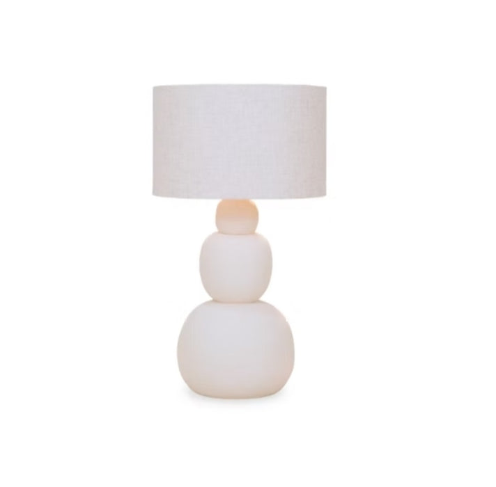 Minimalist off-white ceramic table lamp featuring a smooth, three-tiered stacked organic ball base and a matching linen fabric drum shade