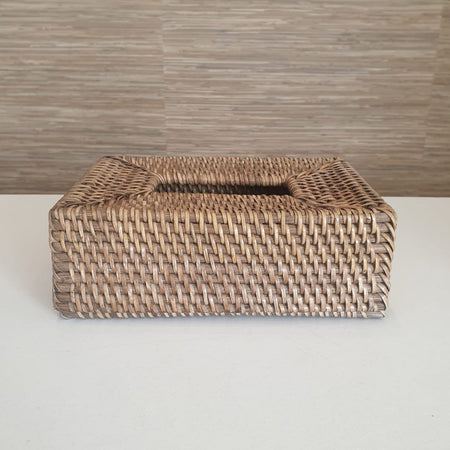 Woven tissue box cover on a white surface with a wooden background