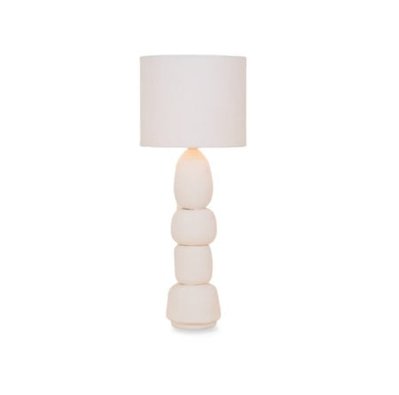 Tall white ceramic statement lamp with a four-tiered stacked asymmetrical pebble base and a tall linen drum shade